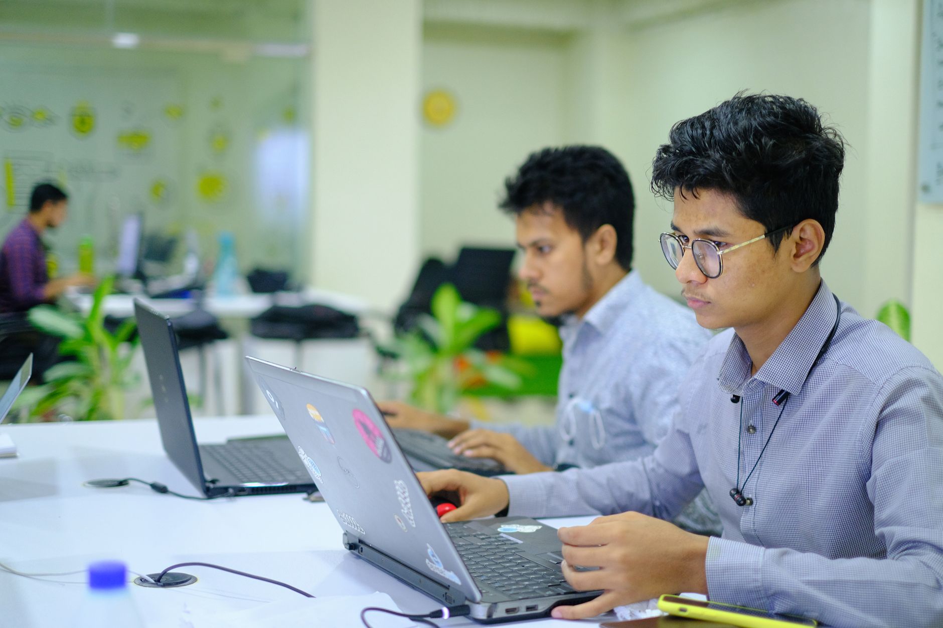 Two team members working side by side on laptops in the office